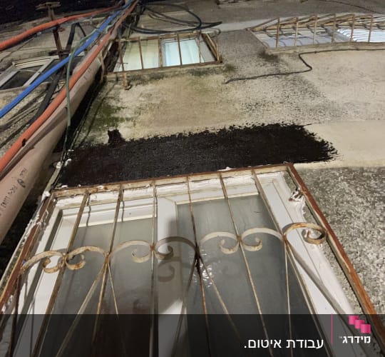 איטום קיר חיצוני עם חומר שחור ליד חלון